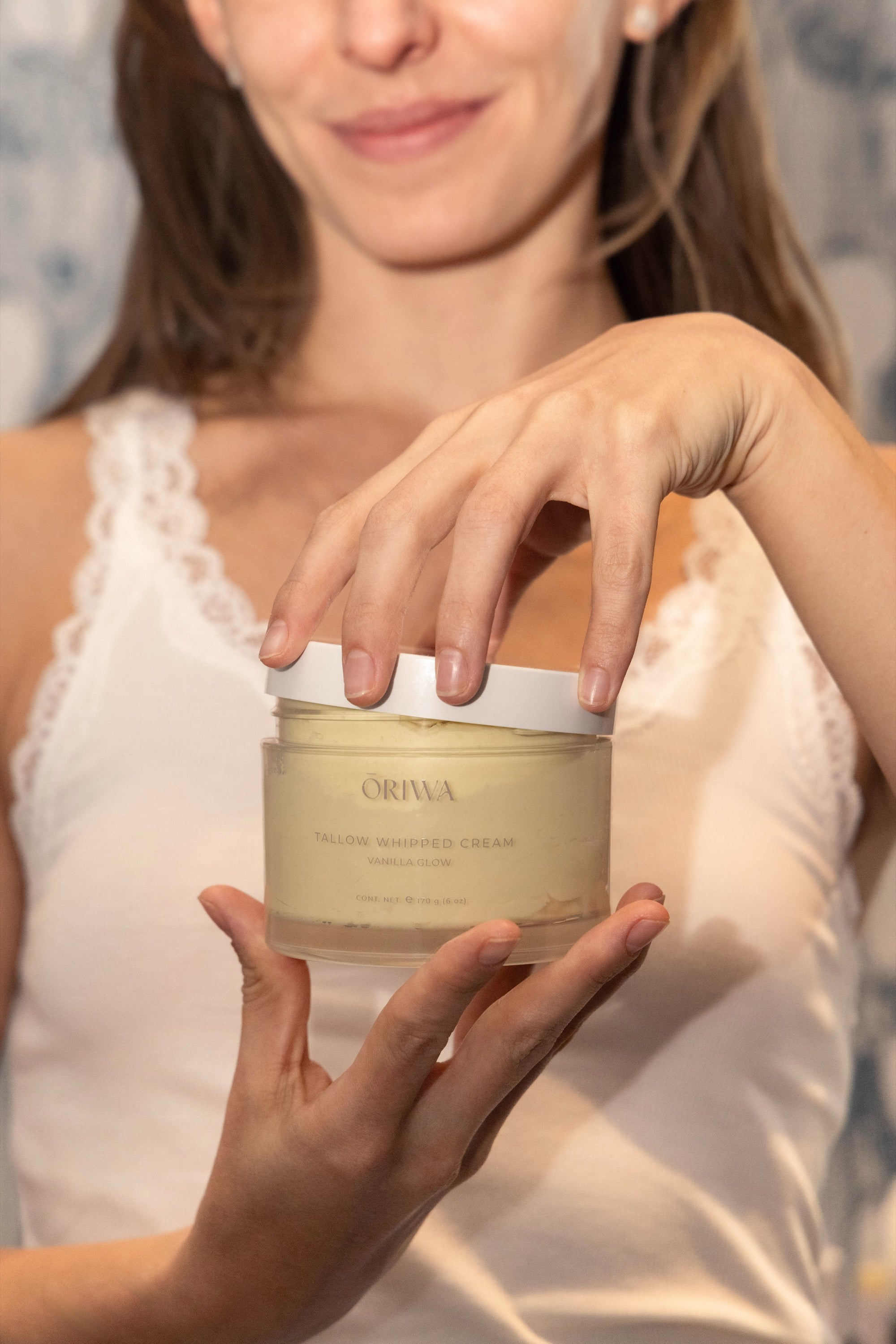 Un tarro de crema de tallow sostenido frente a la cámara.